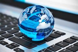 Creative abstract global communication and internet business telecommunication concept: macro view of crystal Earth globe on laptop or notebook keyboard with selective focus effect